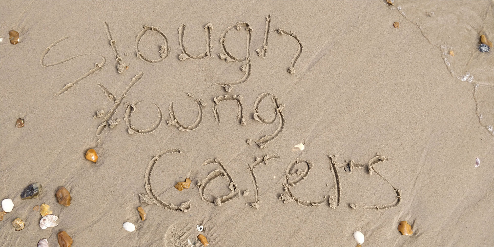 Young carers written in the sand